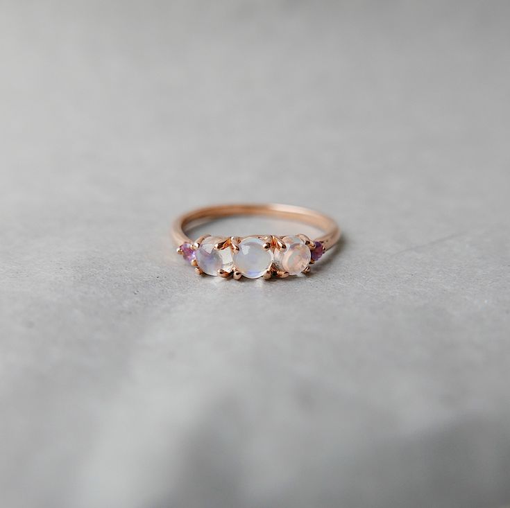 This Hailey Moonstone Ring is a captivating addition to your stack or on its own. If you know me, you know my love for moonstones. The glow of a moonstone is undeniable. This version of the Hailey is set with 3 cabachon moonstones and flanked with two small amethysts. The perfect ring to have a little slice of magic on your finger. This ring represents the complexity and grace of the woman wearing it. Details: 14k gold band (available in white, rose gold, and yellow gold) Moonstones measure abou Sparkly Rings, Raw Stone Engagement Rings, Cute Promise Rings, Moonstone Rings, Dainty Rings, Sparkly Ring, Ring Simple, Cute Rings, Pretty Rings