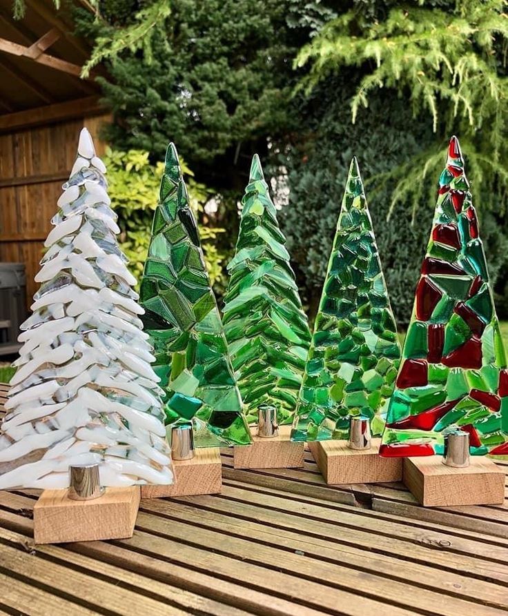 several different colored glass trees sitting on top of a wooden table