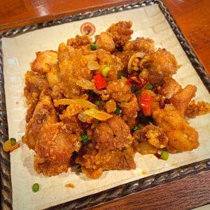 fried food on a white plate sitting on top of a wooden table