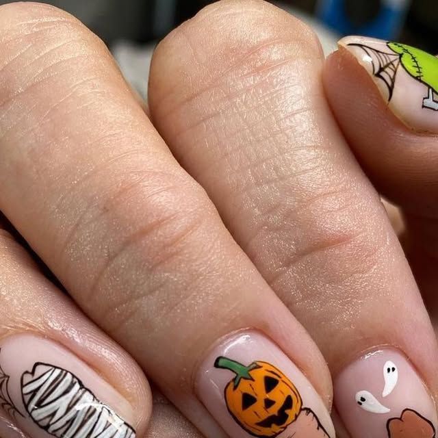 a woman's hand with halloween themed nail art on her nails and an orange pumpkin