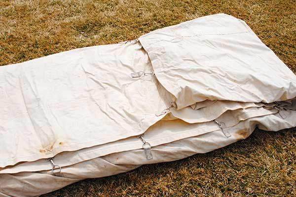 a white tarp laying on top of a grass covered field next to a fire hydrant