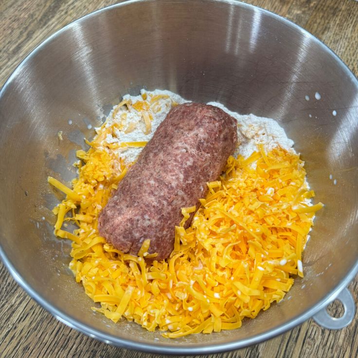 a sausage and sauerkraut in a metal bowl on a wooden table top