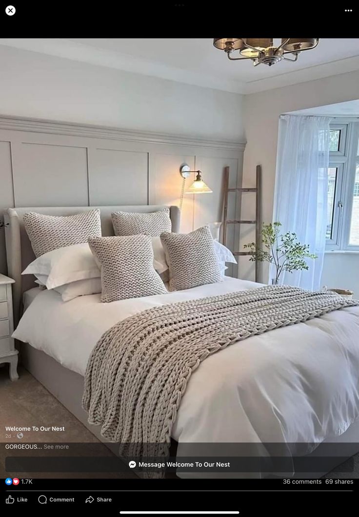 a large bed sitting under a window next to a white dresser and lamp in a bedroom