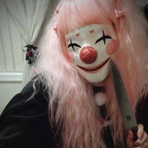 a creepy clown with pink hair holding a knife