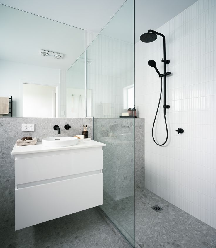 a bathroom with a sink, mirror and shower head mounted to the side of the wall