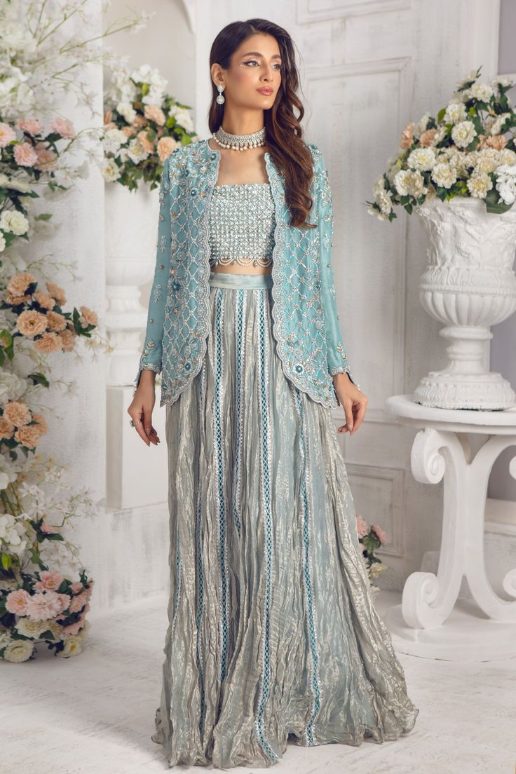 Modernize your wardrobe with this stylish Jacket outfit, cut from Pure raw silk featuring botanical embroidery in silver & antique gold with dabka, nakshi, sequins, zari, pearls, crystals and resham work. Heavily embellished bodice in shades of silver with scalloped beaded tassel details adds a modern touch to this outfit. Paired with shimmer tissue crushed lehenga & dupatta trimmed with lace details, this piece is one for the ages and timeless season and season again Jacket Fabric: Pure 80gms R Crushed Lehenga, Crushed Fabric Dress, Crushed Fabric Dress Indian, Party Wear Choli With Long Sleeves And Mirror Work, Hand Embellished Anarkali Set For Reception, Party Wear Hand Embellished Anarkali Set For Reception, Embellished Long Sleeve Party Wear Sets, Hand Embellished Anarkali Raw Silk Set, Party Wear Long Sleeve Choli With Mirror Work