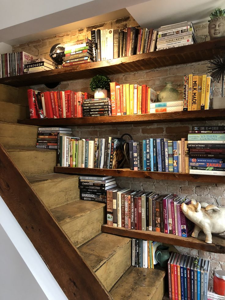 the bookshelves are filled with many different types of books and there is a cat statue on top