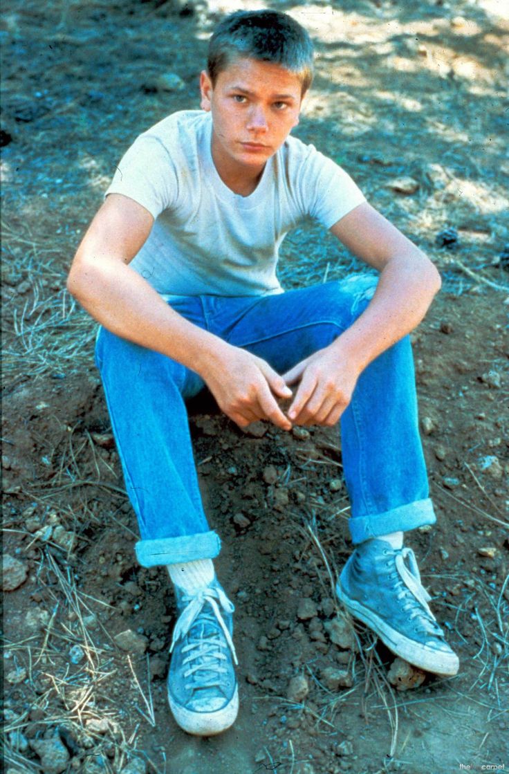 a young man sitting on the ground with his legs crossed