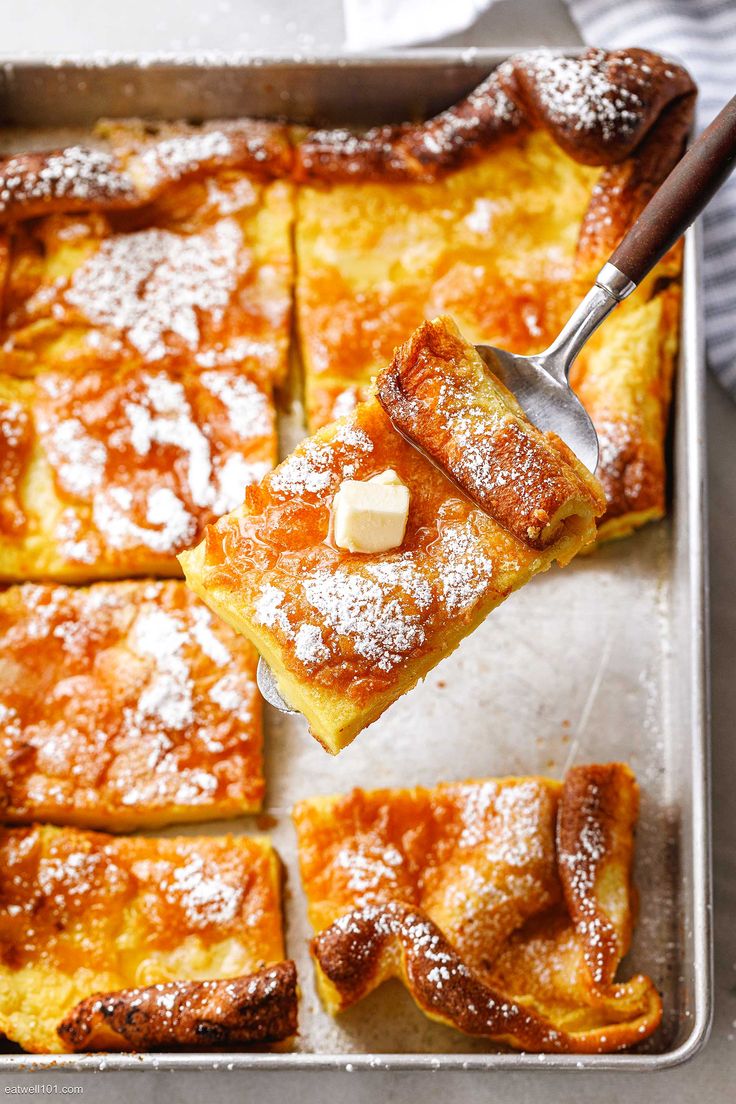 a pan filled with desserts covered in powdered sugar