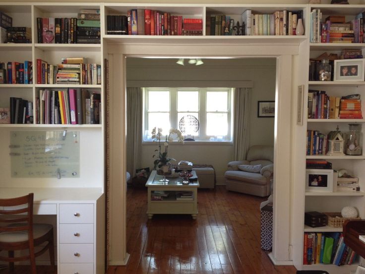 a living room filled with lots of furniture and bookshelves next to a window