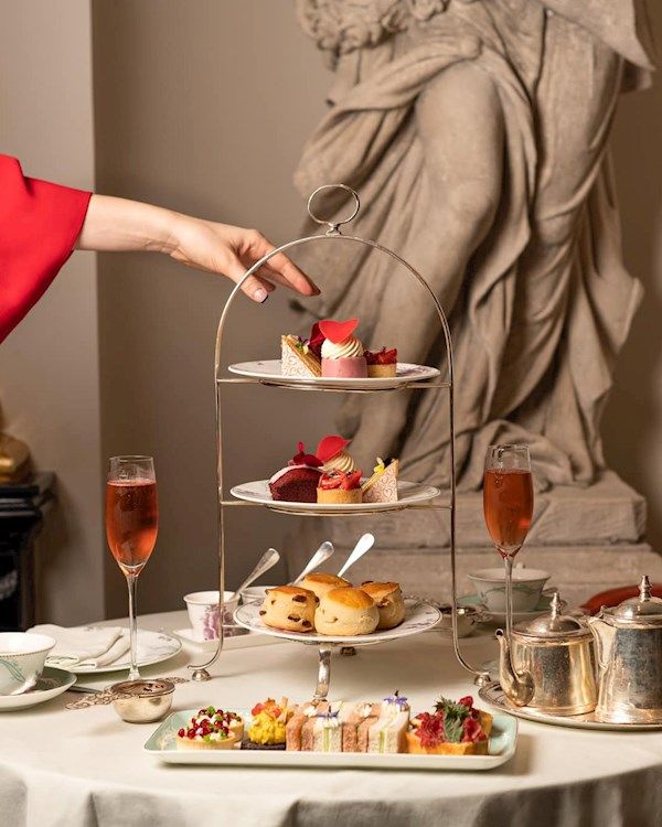 a woman is serving desserts at a table with a statue in the back ground