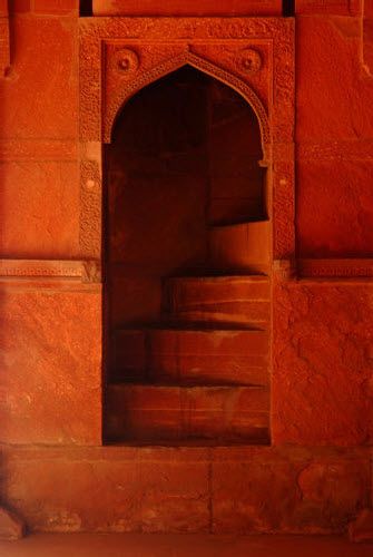 an old red building with steps leading up to the door and window on it's side