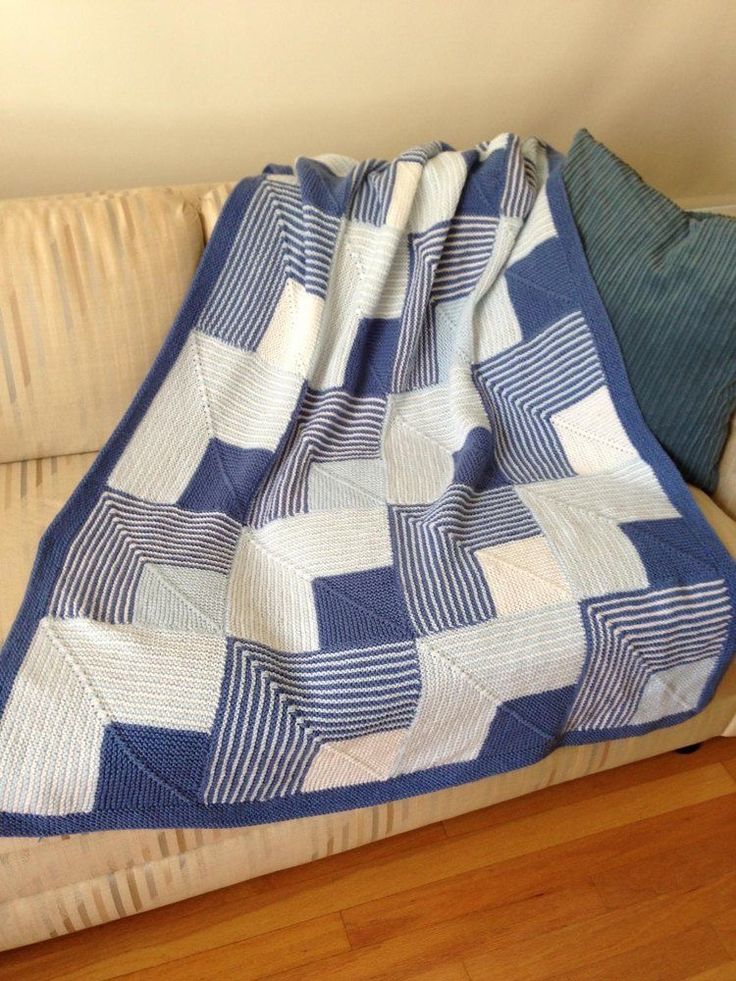 a blue and white blanket sitting on top of a couch next to a wooden floor