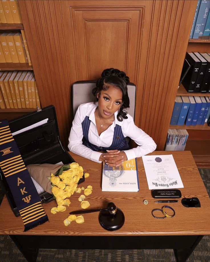 a woman sitting at a desk in front of a book case and some other items