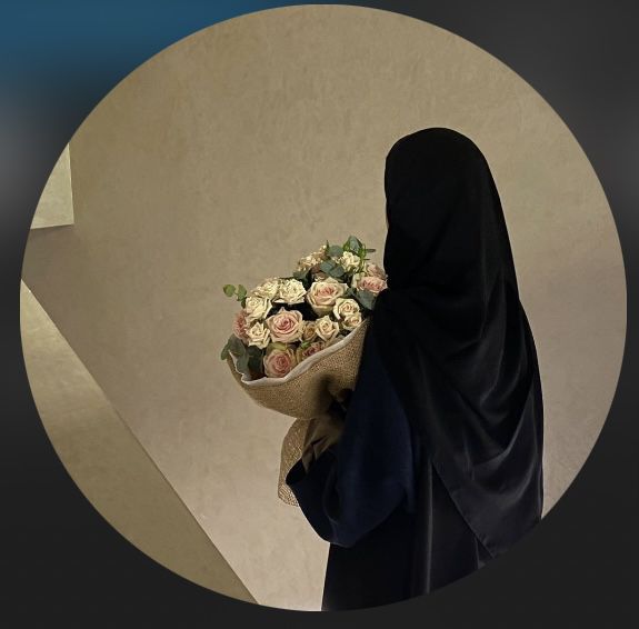 a woman in a black robe holding a bouquet of flowers and looking down at the ground