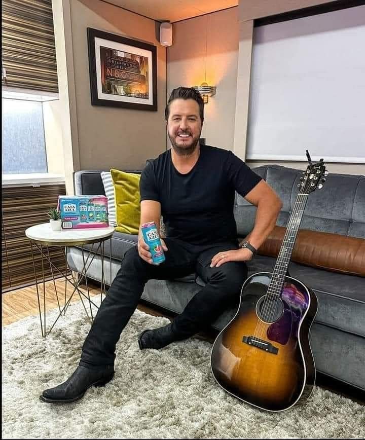 a man sitting on top of a couch next to a guitar and a bottle of water