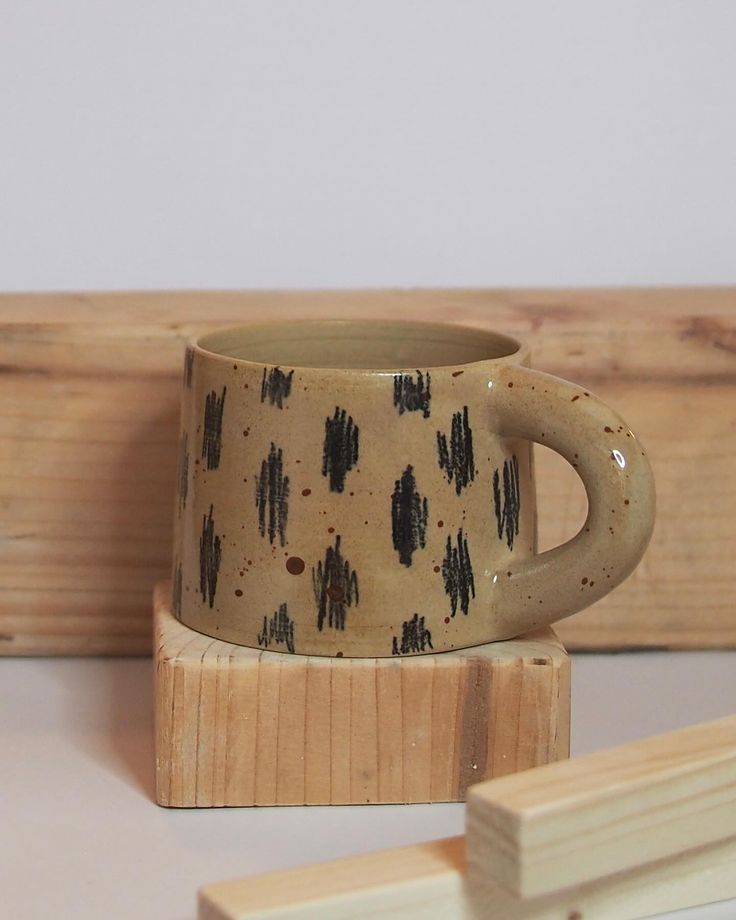 a coffee cup sitting on top of a wooden block next to a piece of wood