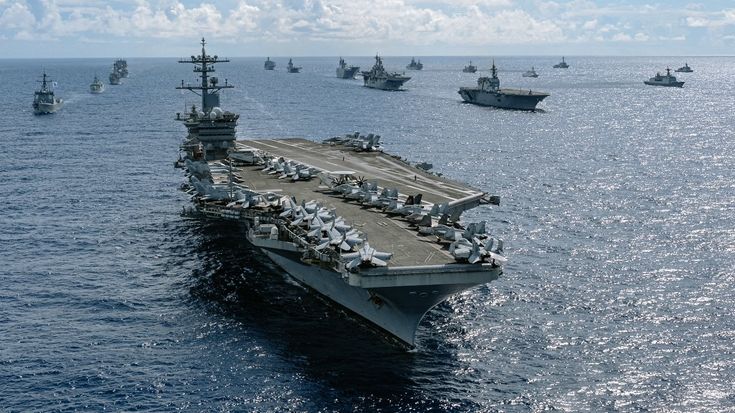 an aircraft carrier in the ocean with other ships