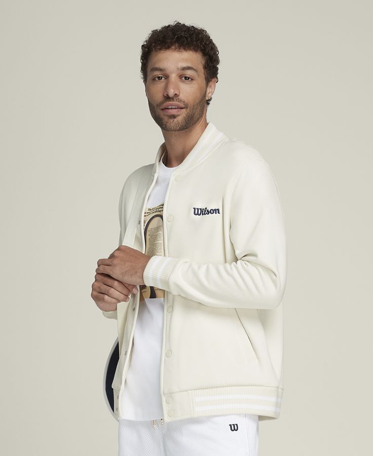 Suit up in timeless sport style. An easy layer to snap over a polo or tee, the Hudson Bomber Jacket brings a touch of luxury to the court. It's made of premium tricot fabric that feels comfortably breathable and wonderfully soft against your skin. Wilson branding accents this bomber, nodding to a hundred-year legacy on the court. | Wilson Men's Hudson Bomber Jacket White Baseball Collar Track Jacket For Fall, White Track Jacket With Baseball Collar For Fall, White Cotton Track Jacket With Baseball Collar, White Fall Track Jacket With Baseball Collar, White Sporty Outerwear With Baseball Collar, Sporty White Outerwear With Ribbed Collar, White Baseball Collar Outerwear For Sports Season, Classic Sports Sweatshirt With Ribbed Cuffs, Collegiate Track Jacket With Ribbed Cuffs For Fall