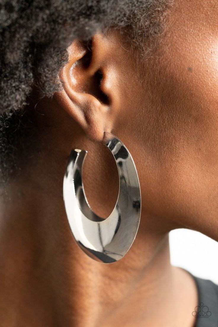 a woman wearing large silver hoop earrings