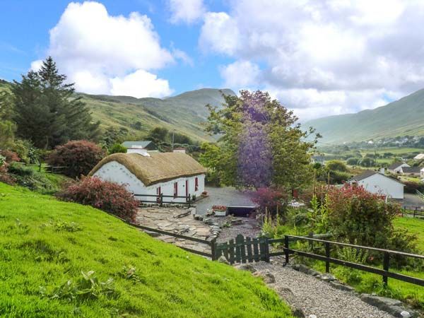 a small house with a thatched roof in the middle of a lush green valley