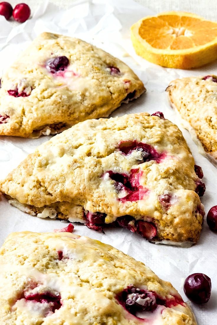 cranberry orange scones on parchment paper next to an orange slice