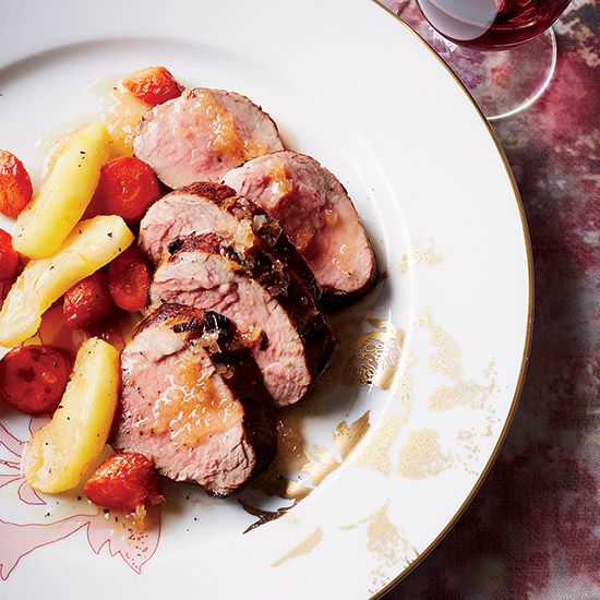 a white plate topped with meat and veggies next to a glass of wine