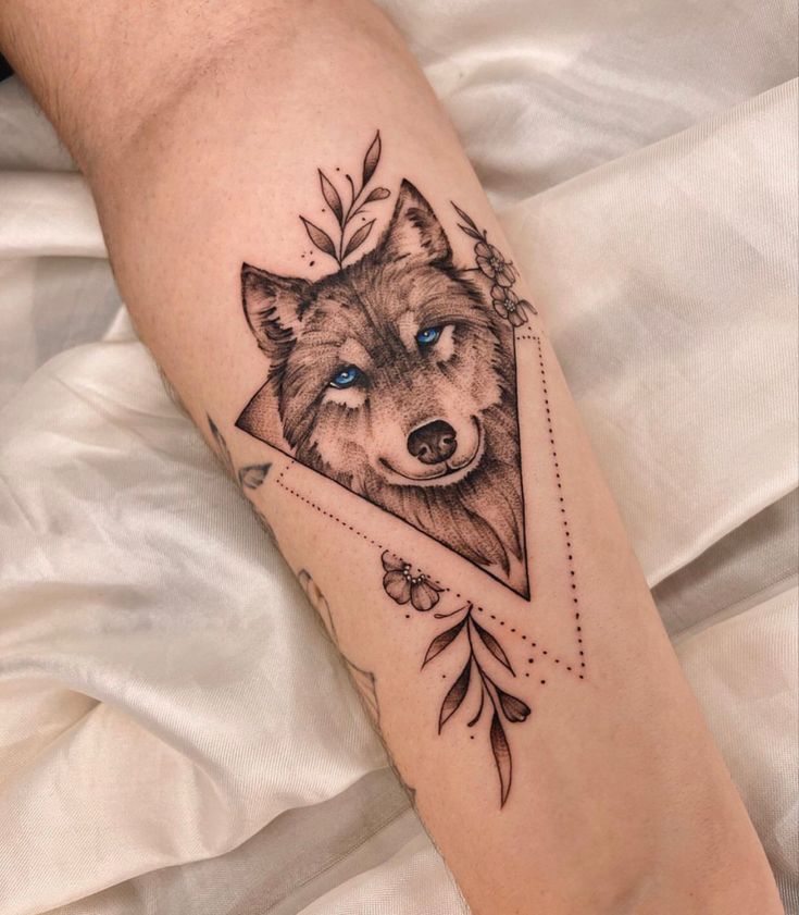 a tattoo on the leg of a person with a wolf head and leaves around it