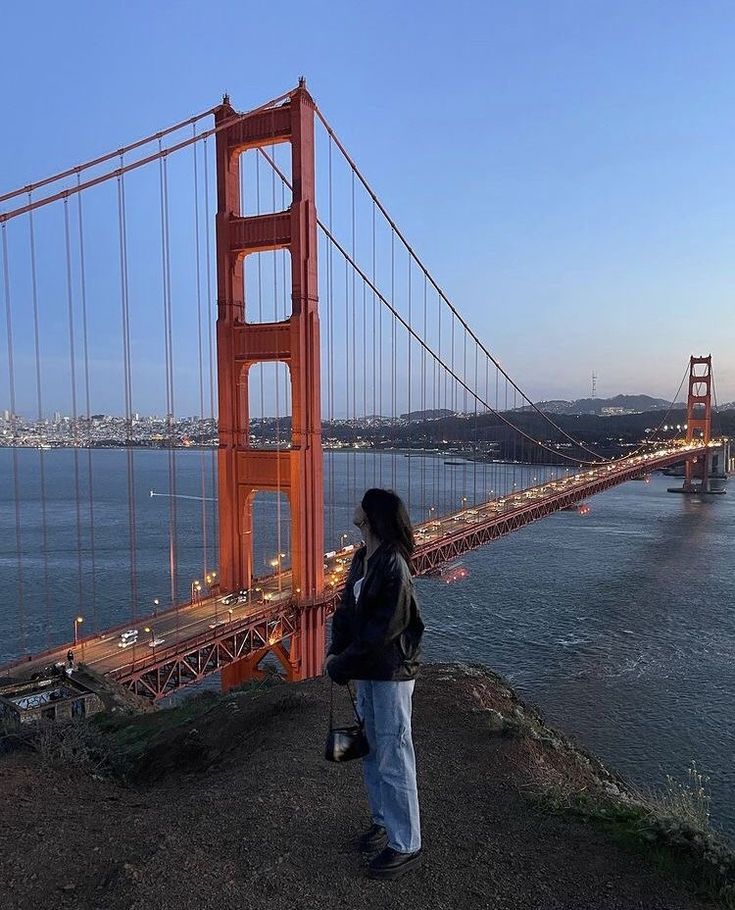 a woman standing in front of the golden gate bridge