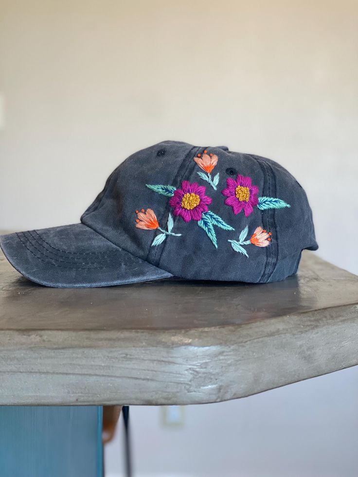 Unique hand embroidered baseball cap. Has a bright floral design on a vintage style hat. Its a really fun accessory with one of a kind details. The hat is a one size fits most with an adjustable strap. Casual Hand Painted Hat, One Size Fits Most, Vintage Black Baseball Cap For Spring, Casual Hand Painted Cap, Casual Hand Painted Hat, Vintage Adjustable Brimmed Baseball Cap, Fun Spring Brimmed Baseball Cap, Whimsical Adjustable Cap, Fun Spring Baseball Cap, Fun Hats With Embroidered Logo One Size