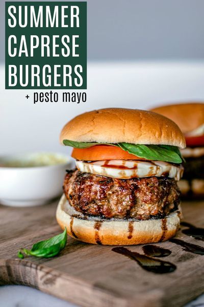 two burgers sitting on top of a wooden cutting board