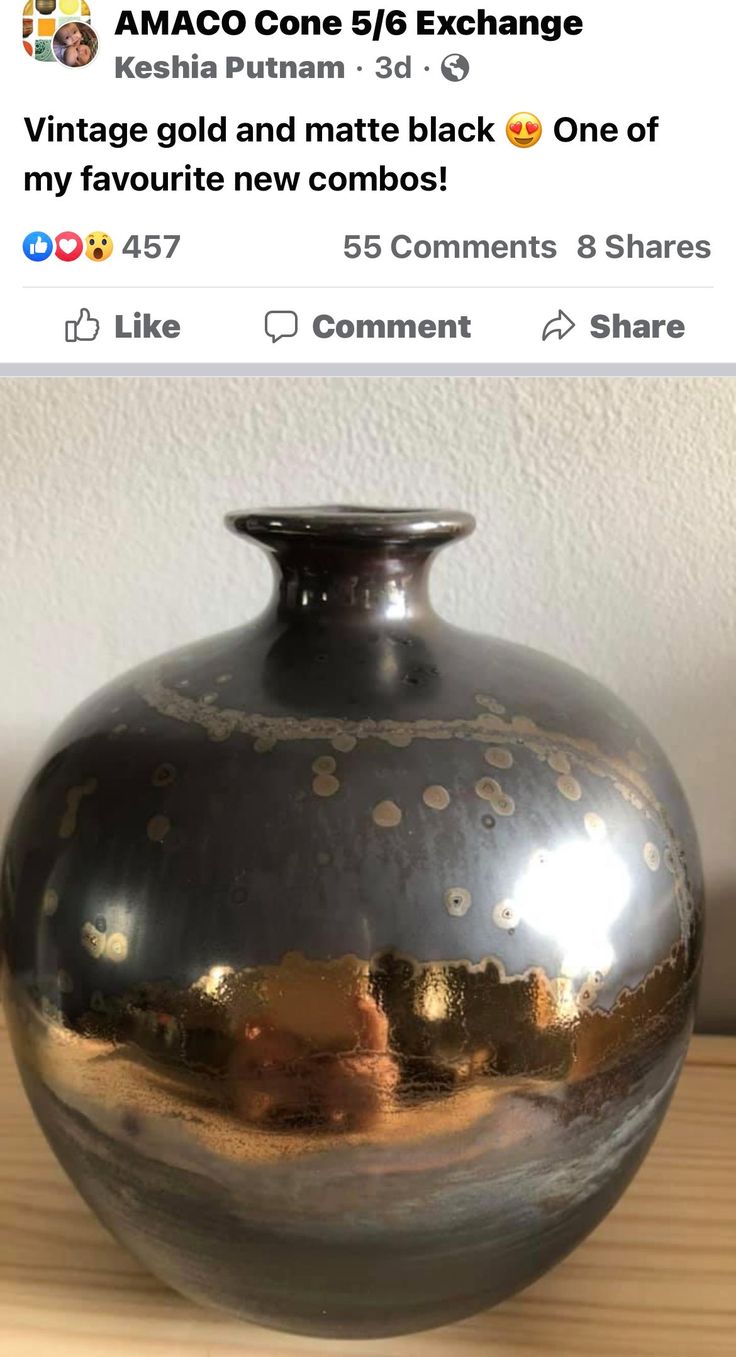 a large black vase sitting on top of a wooden table