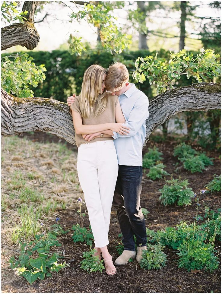 a couple embracing each other in front of a tree