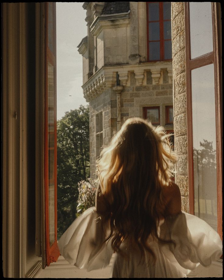 a woman standing in front of a window looking out