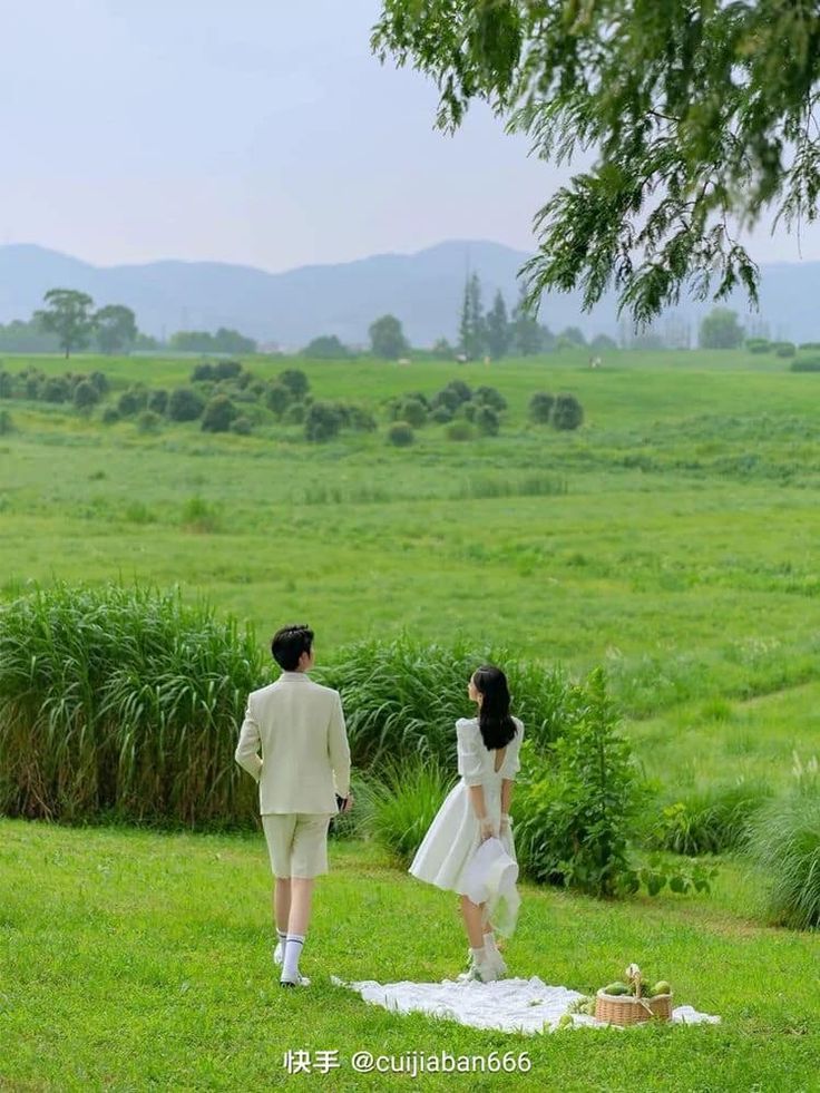 two people standing on top of a lush green field