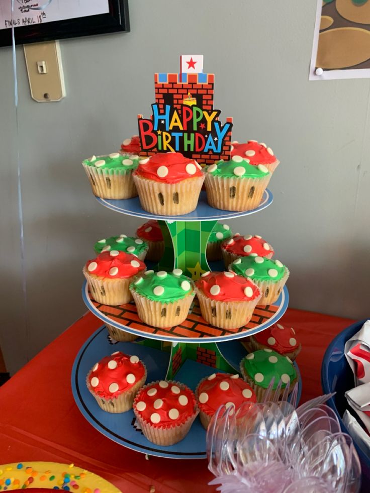 cupcakes are stacked on top of each other in front of a birthday cake