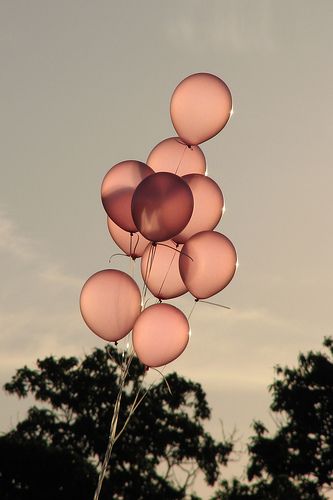 a bunch of balloons floating in the air with trees in the backgrounnd