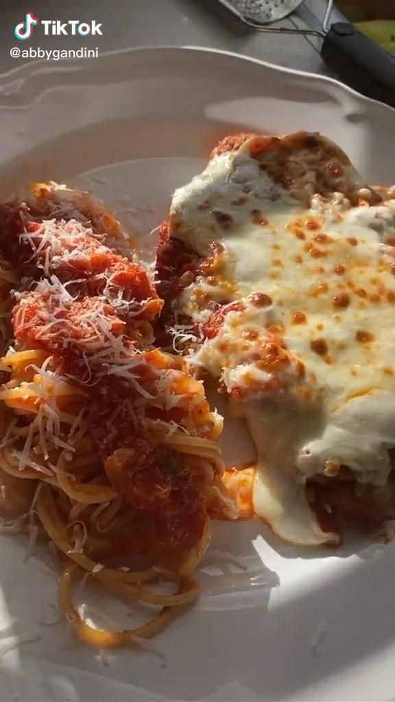 a white plate topped with lasagna covered in sauce and cheese on top of it