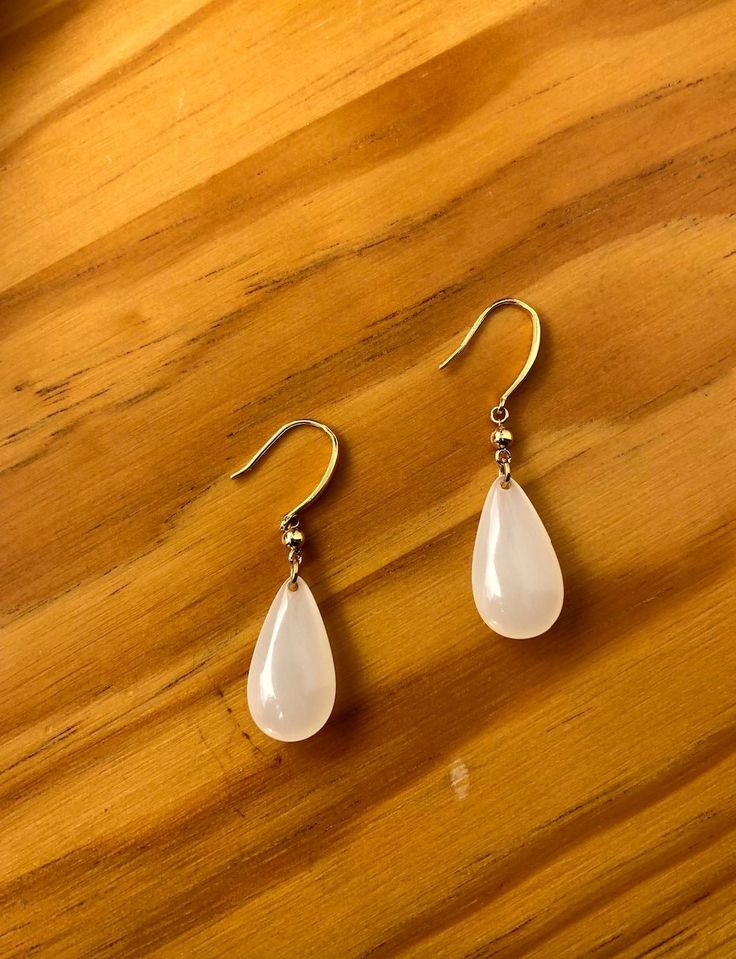 A pair of cute genuine white jade teardrop earrings, hand-made with 925 sterling and plated with 14k gold in vintage designs. The drop/dangle style is simple and elegant. The delicate white jades come from Burma and are grade-A Gemstones. The rest parts are handmade with high-quality 925 Sterling Silver plated with 14k gold. The minimal and stylish design shows a taste of elegance and royalty.  Some features of these lovely gold white jade earrings are: *High-quality guaranteed Made from genuine white jades and pure 925 sterling silver plated with 14k gold. *Charm & elegant Simple and royal teardrop design. *Measurement Each drop is about 1.5'' long and 0.5'' wide. *100% Satisfaction Guarantee Gift-worthy packaging included! Please include a message if you have a special request upon payme Elegant White Jade Jewelry, Jade Pearl Drop Earrings As Gift, Elegant Jade Teardrop Earrings, White Jade Earrings For Gift, Elegant Teardrop Jade Earrings, White Minimalist Teardrop Dangle Earrings, Elegant White Jade Earrings, White Jade Dangle Jewelry, Delicate White Dangle Teardrop Earrings