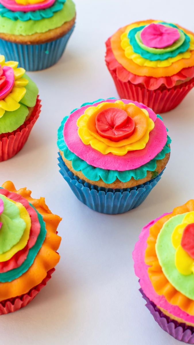 cupcakes decorated with colorful frosting on a white surface