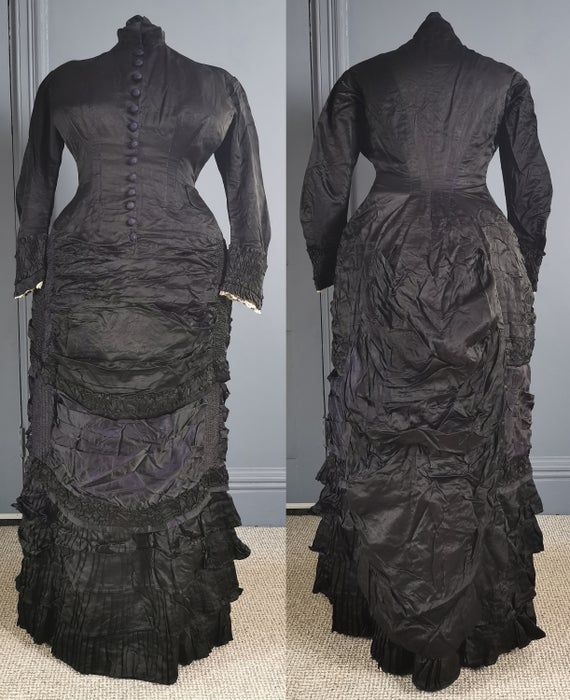 A superb, gothic Victorian antique bustle dress for mourning, dating to the early 1880s / natural form era - excellent condition, and a rare larger size. One piece, in a glossy two tone silk, black, the reverse in purple, the dress reflecting subtle purple tones. Closely fitted to the body, the bodice boned, fastening in the front with woven dome buttons in purple from neck to hip. Small collar, and a small waist patch pocket. Long fitted sleeves, with gathered cuffs and lace trim on the inner e Black Victorian Dress For Costume, Black Victorian Dress Costume, Victorian Dress With Ruffles For Theater, Victorian Ruffled Dress For Theater, Black Historical Victorian Costume Dress, Black Victorian Dress With Ruffles, Historical Black Victorian Costume Dress, Fitted Vintage Victorian Dress For Theater, Ruffled Victorian Dress For Theater