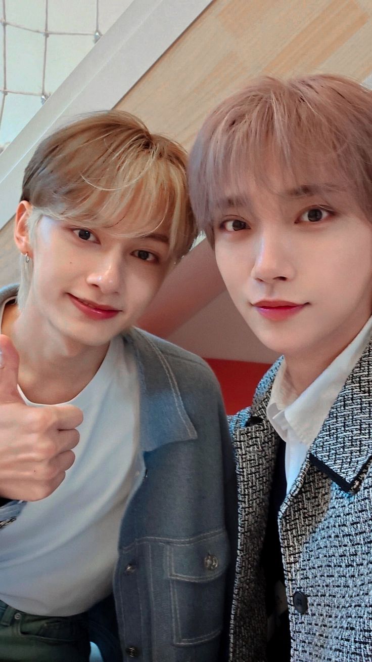 two young men standing next to each other giving the thumbs up sign with their hands