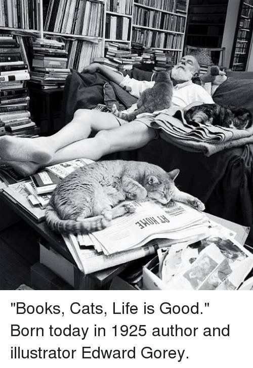 black and white photograph of man laying on couch with cats sleeping next to him in front of bookshelves