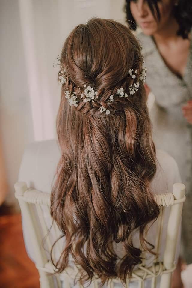 a woman sitting in a chair with her hair styled into a half updo and flowers