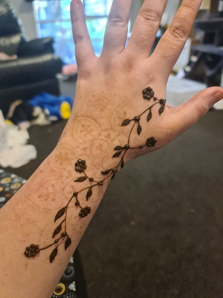 a person's hand with a flower tattoo on the middle of their left arm