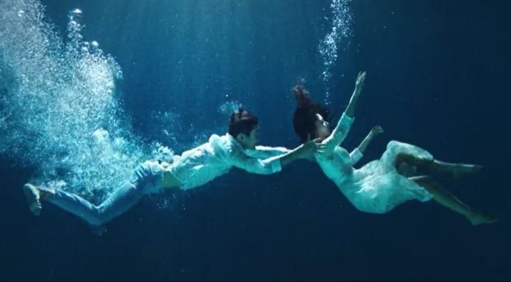 two people are swimming in the water with their backs to each other and one person is falling off his back