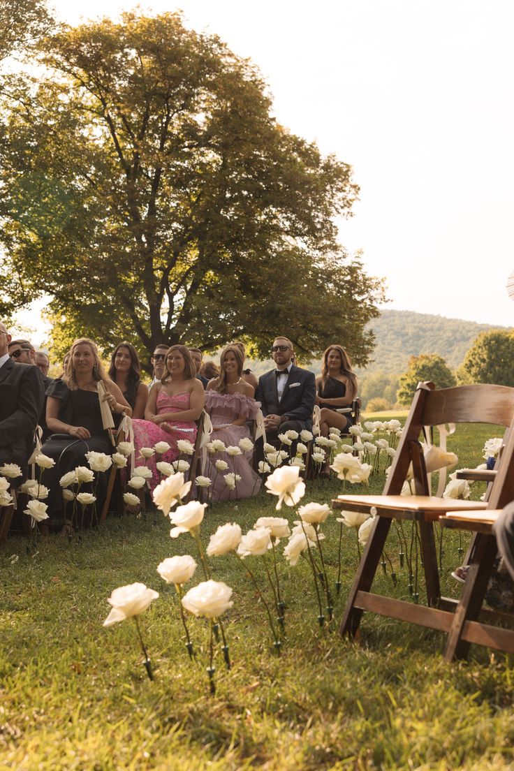 a group of people sitting on top of a lush green field next to each other