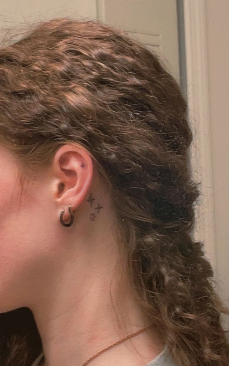 a woman with curly hair and piercings on her ear