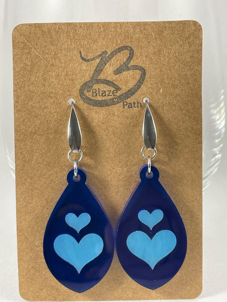 Lapis blue acrylic teardrop earrings with light blue inlay hearts on stainless steel ear wires with teardrop accent Valentine's Day Blue Heart Earrings, Blue Heart-shaped Earrings With Ear Wire, Blue Heart Earrings For Gift, Blue Heart-shaped Earrings For Valentine's Day, Blue Heart Charm Earrings For Valentine's Day, Blue Heart Earrings For Valentine's Day, Blue Sterling Silver Heart Earrings For Valentine's Day, Blue Pierced Heart Earrings, Blue Heart Drop Earrings