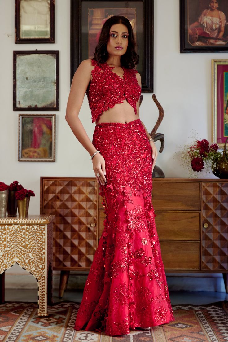 This structured red mermaid lehenga set personifies the emblem of romantic glamour. The set features intricate embroidery of cutdana work and dori with red sequins, beads, and floral applique work adorning both the skirt and blouse. Its focal point is the tassel detailing flowing at the bottom of the skirt with cute flower motifs made of sequins. • Sleeveless blouse with floral applique detailing highlighted with nalki crystals and beads.• Blouse contains a metal hook on the front side.• Heavily embroidered dupatta with botanical motifs detailing accentuated with sparkling sequins and crystals. • Lehenga skirt adorned with floral applique handwork detailing and drop-down tassels adorning the bottom of the skirt. • Lehenga contains a left zipper for support along with a metal hook.From Mole Red Sleeveless Lehenga For Party, Sleeveless Red Lehenga For Party, Red Sleeveless Party Lehenga, Red Sharara With Mirror Work For Party, Red Floor-length Sets For Reception, Red Fitted Sets With Mirror Work, Red Embellished Party Wear Set, Glamorous Sequined Floor-length Sets, Glamorous Floor-length Sequin Sets